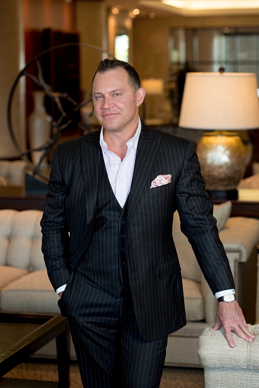 Man in a pinstripe suit standing indoors.