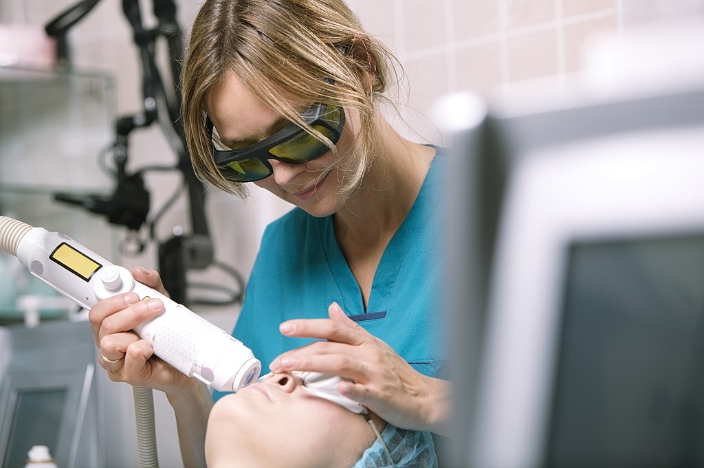 Medical professional using a laser treatment device.