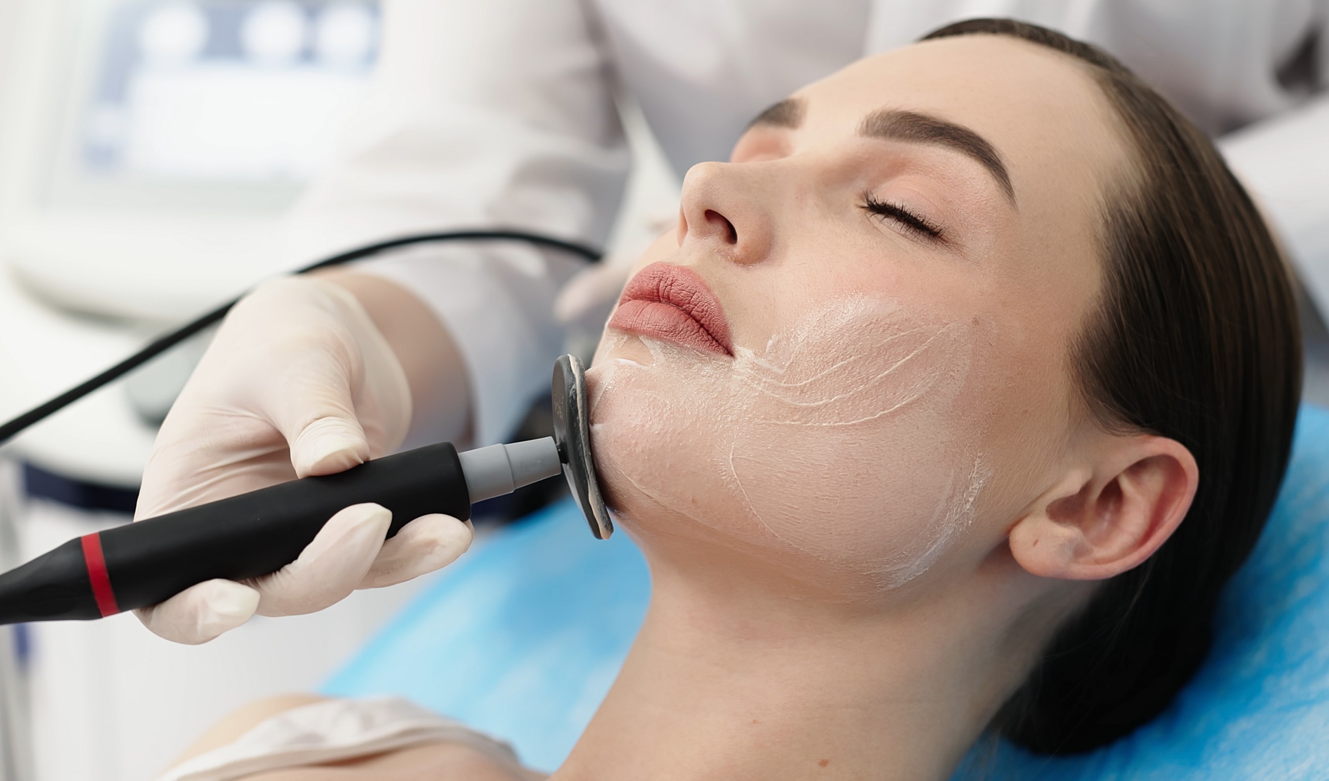 Facial treatment with aesthetic device on patient.