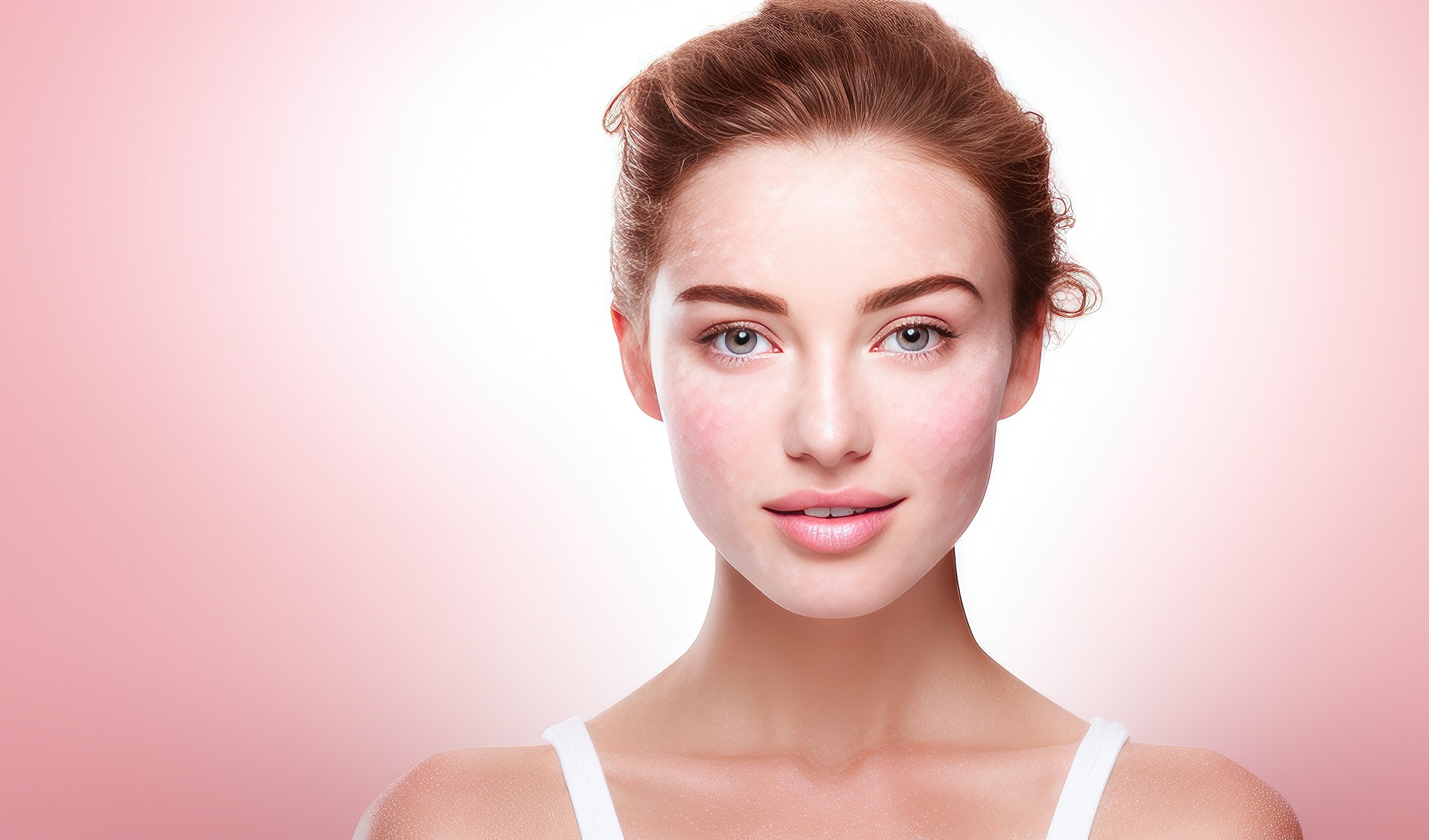 Young woman with flawless skin against pink background.
