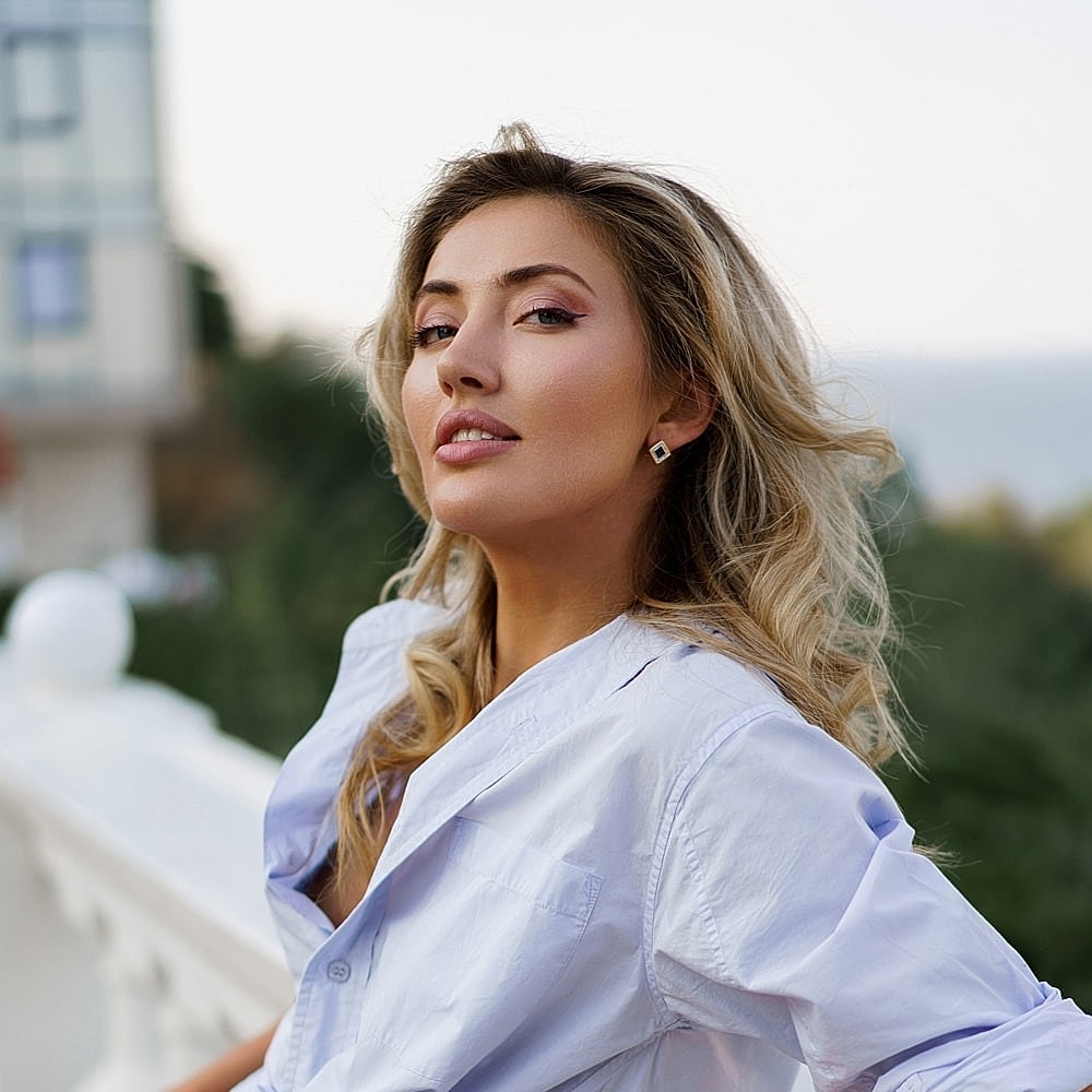 Woman with long hair posing outdoors confidently.