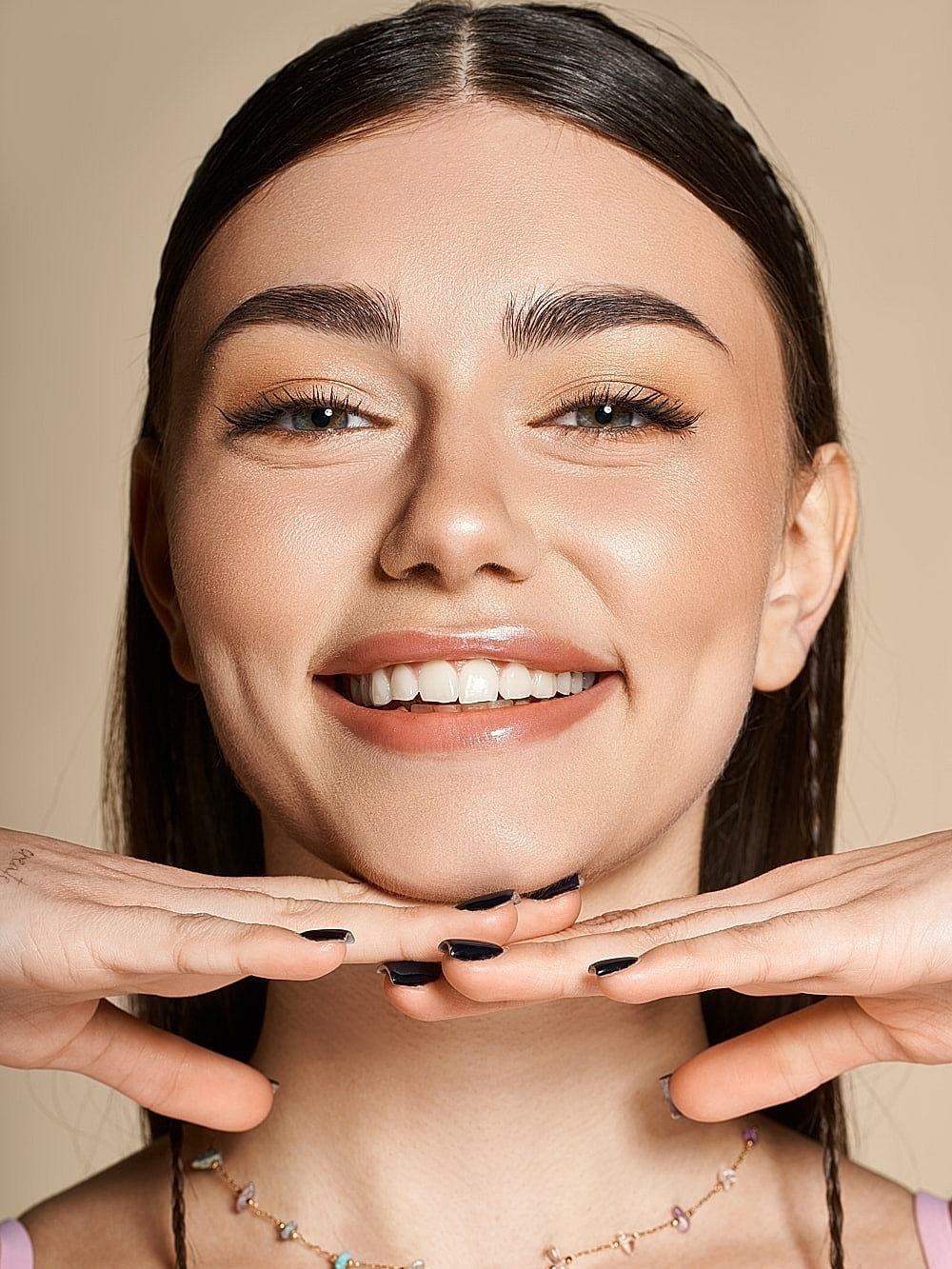 Smiling woman with hands under her chin.